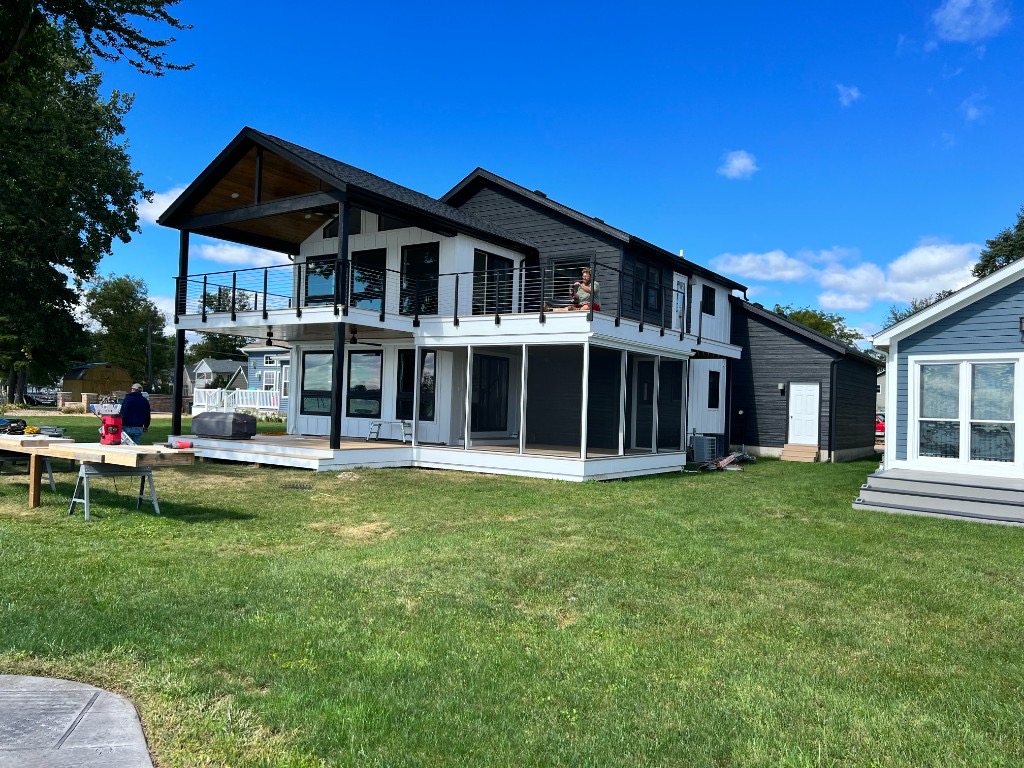 Custom home with black and white siding, upper deck, and screened porch